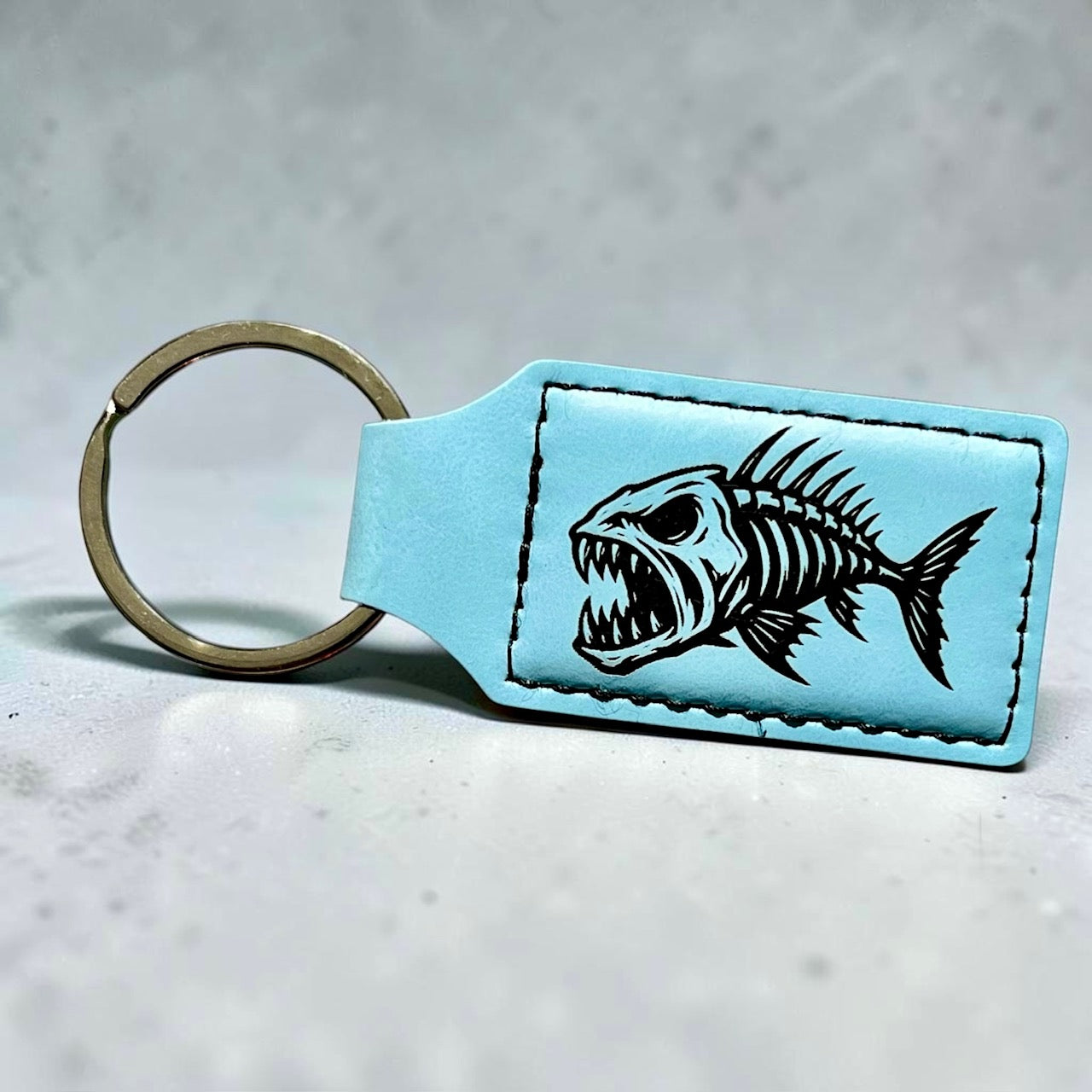 Front view of a Premium Leatherette keychain with a laser engraved fish skeleton.